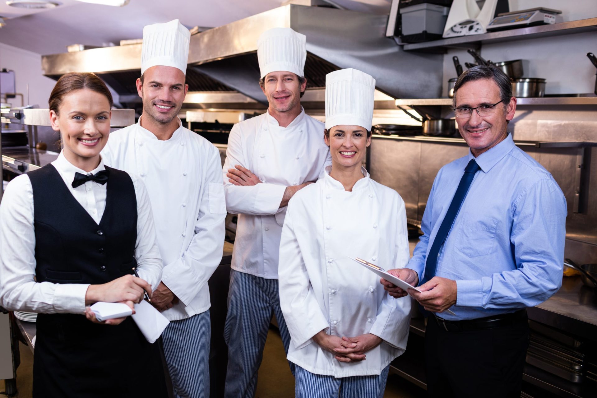 Portrait of happy restaurant team standing together in commercial kitchen