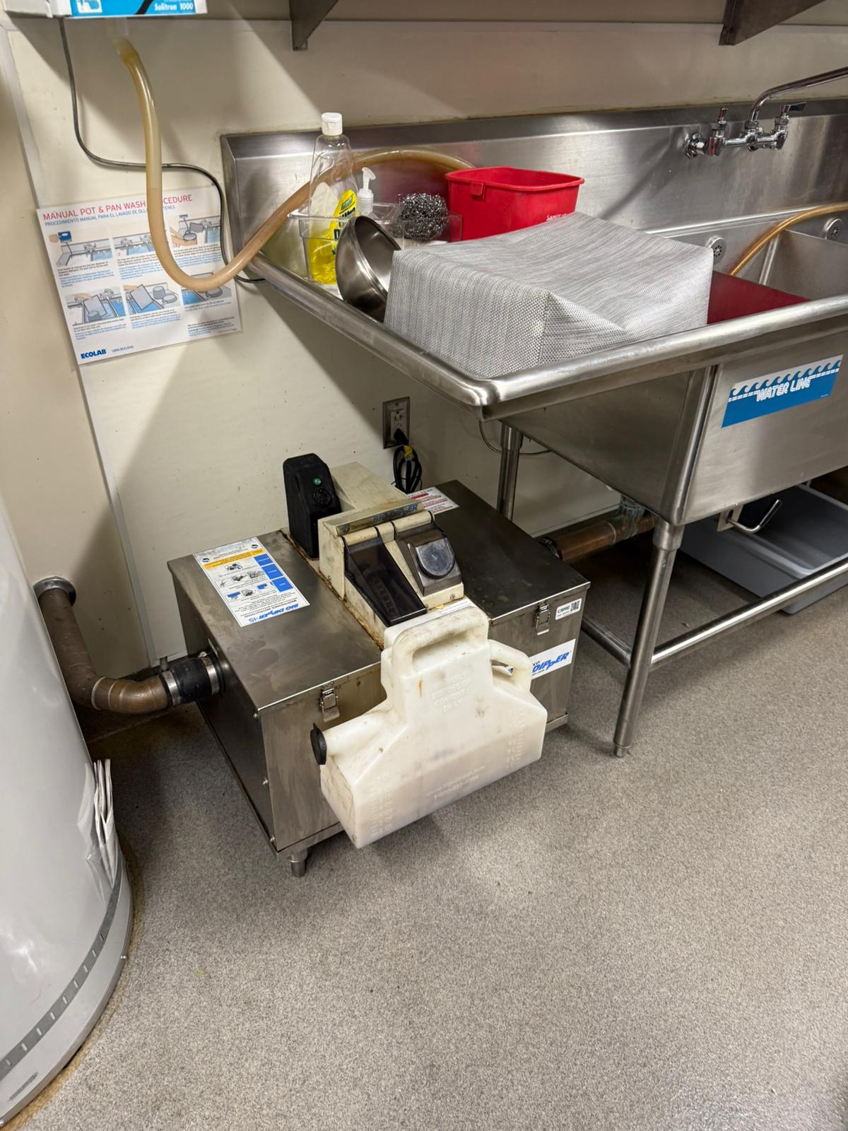 Grease trap cleaning technician servicing a commercial kitchen in Lancaster
